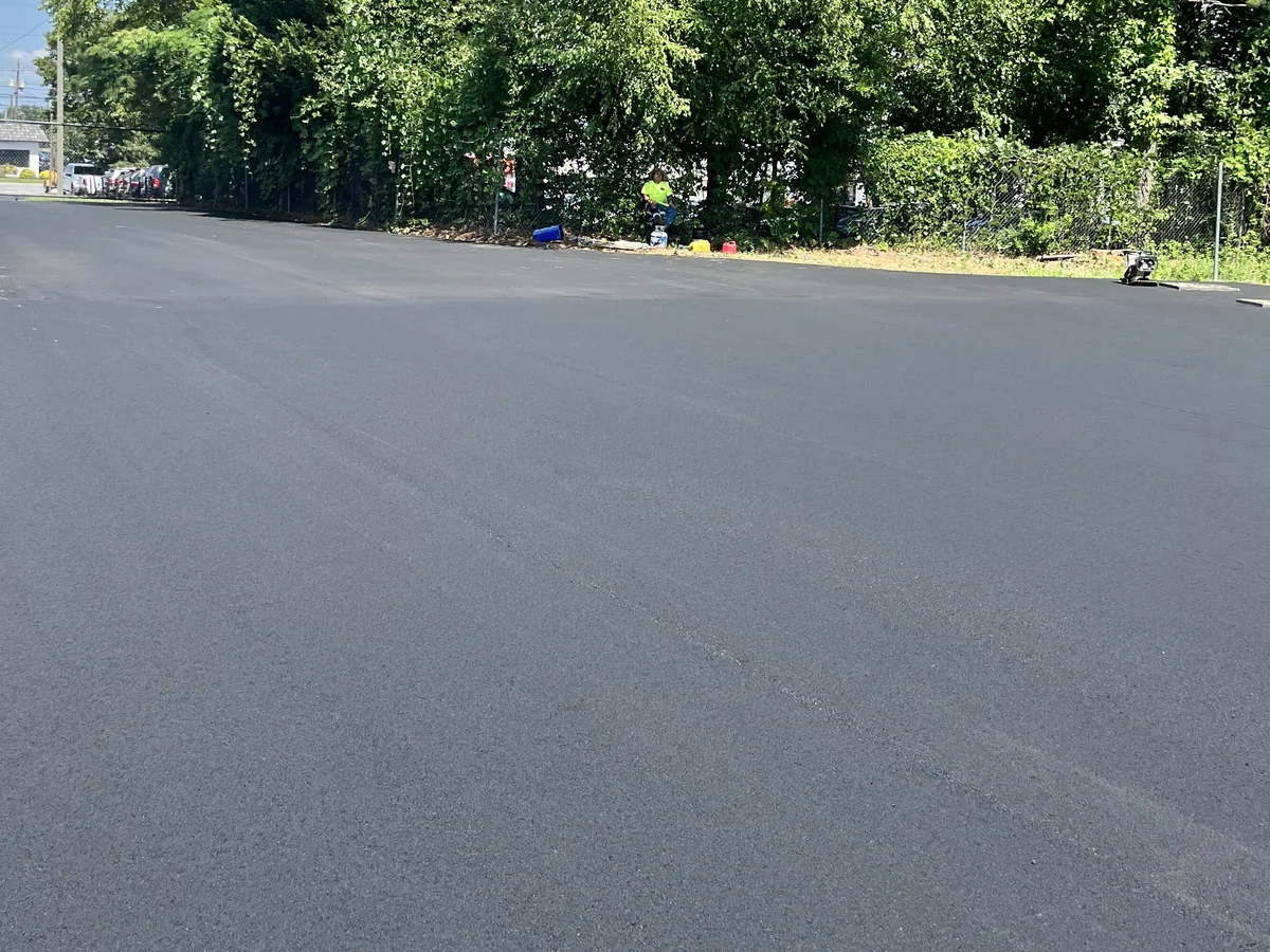 Freshly paved commercial parking lot with a smooth black surface running back to a tree line