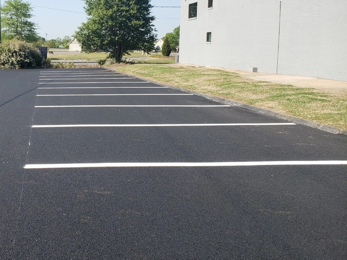 Freshly striped parking stalls in crisp white paint on a new black asphalt lot