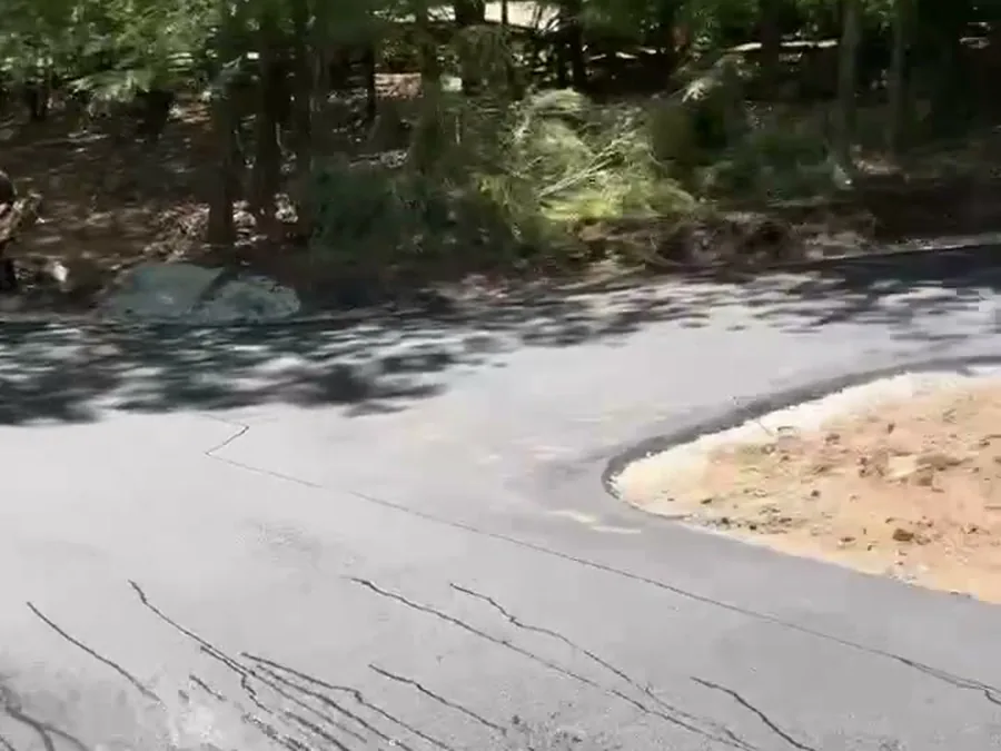 Driveway part-way through sealing, the freshly sealed section dark against the faded original surface