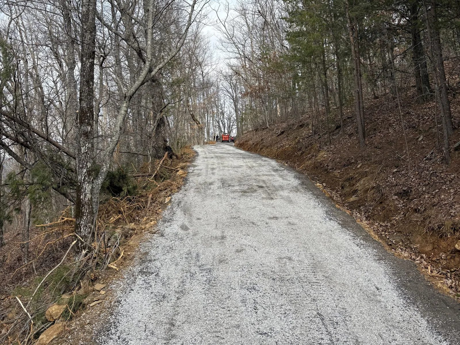 Crushed stone base spread along a wooded lane before the asphalt goes down