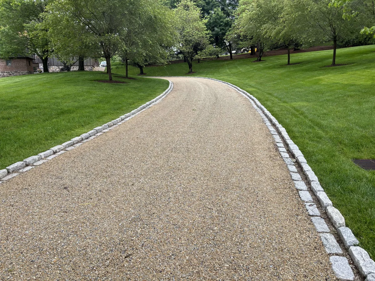 Finished tar and chip driveway with a tan stone surface curving through a green lawn